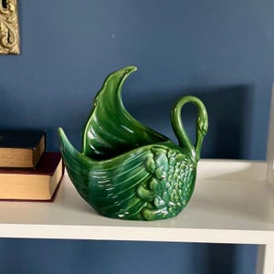 Peut inclure: Un pot en céramique en forme de cygne vert avec un design détaillé. Les ailes du cygne sont déployées pour former un bol.