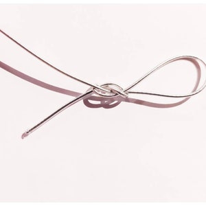 May include: A silver cord tied in a knot on a white background.