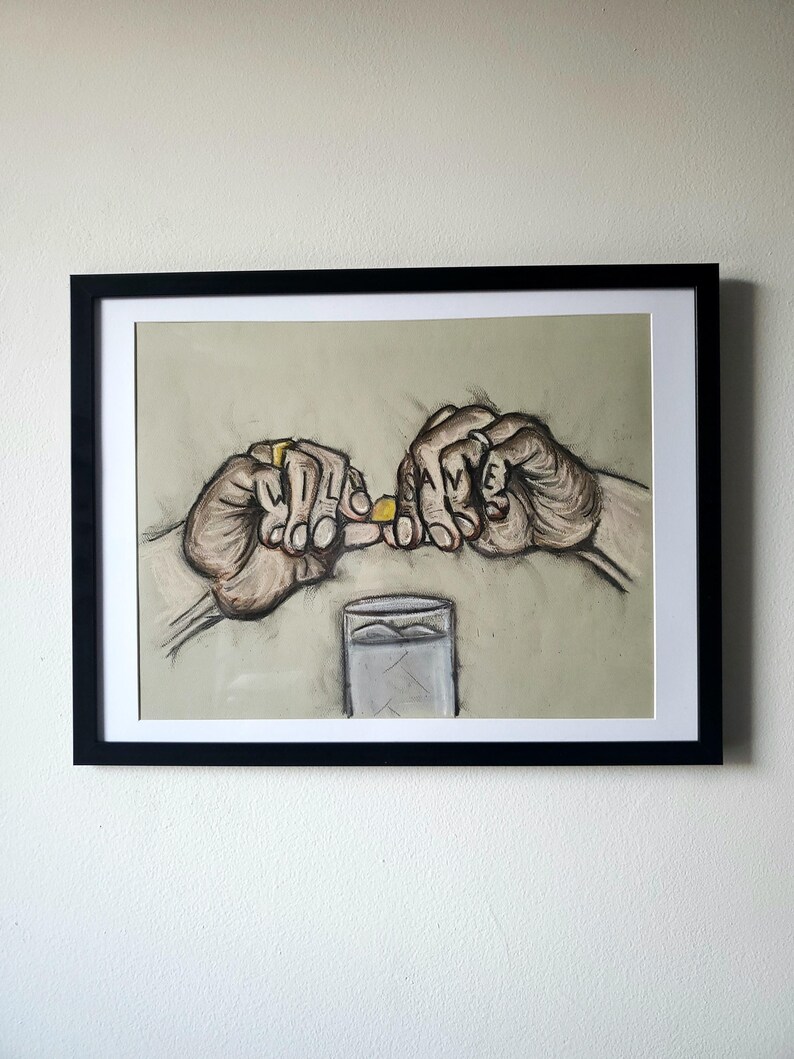 May include: A black and white drawing of two hands holding a small yellow pill. The hands are drawn with detail and the pill is in focus. The drawing is framed in a black frame and is hanging on a white wall.