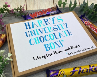 May include: A brown cardboard box with a white label that says "HARRY'S UNIVERSITY CHOCOLATE BOX!" in blue and turquoise lettering. The label also says "Lots of love Mum and Dad x" and "Not to be eaten all in one go!" in black lettering. The box is filled with various chocolate bars, including Wispa, Flake, and Crunchie.