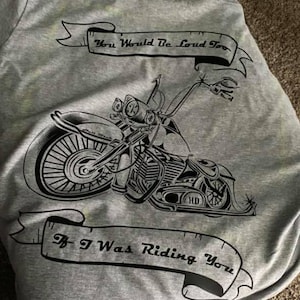 May include: A grey t-shirt with a black and white illustration of a motorcycle. The text on the shirt reads "You Would Be Loud Too If I Was Riding You."