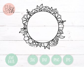 May include: Black and white outline of a floral wreath with a circle in the center. The wreath is made up of leaves, flowers, and vines.