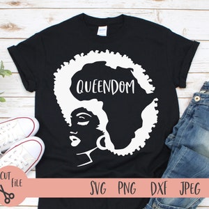 May include: Black t-shirt with a white silhouette of a woman's face with an afro hairstyle shaped like the continent of Africa. The text "QUEENDOM" is written on the silhouette of Africa.