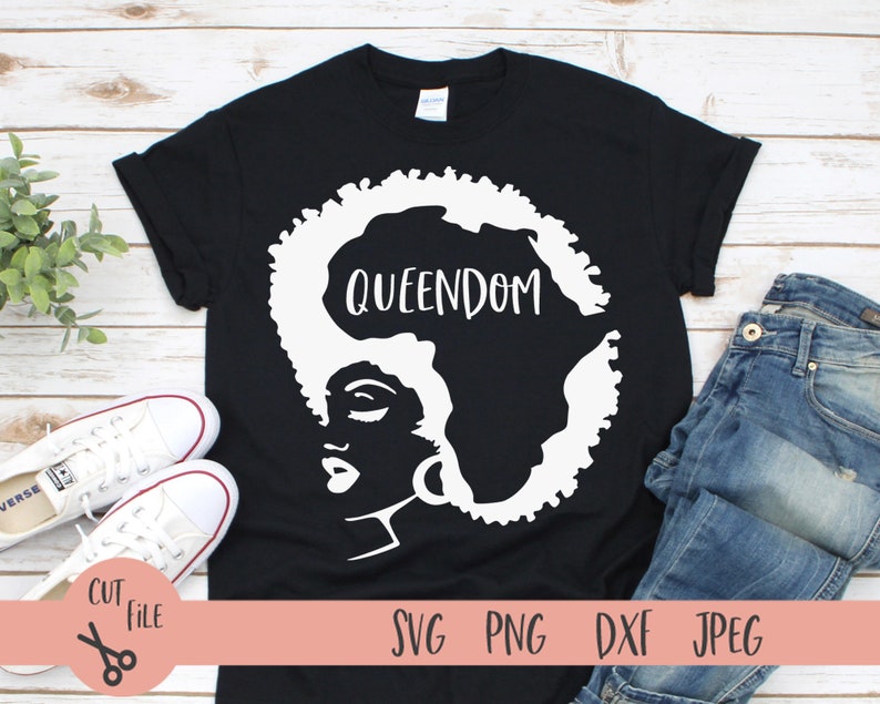 May include: Black t-shirt with a white silhouette of a woman's face with an afro hairstyle shaped like the continent of Africa. The text "QUEENDOM" is written on the silhouette of Africa.