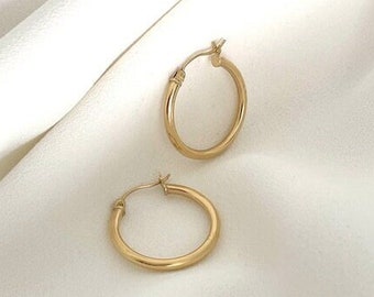 Puede incluir: Un par de pendientes de aro de oro. Los pendientes son simples y clásicos, y serían una gran adición a cualquier colección de joyas.