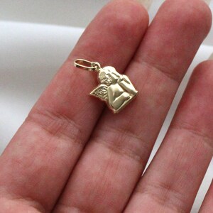 May include: A gold-colored angel charm pendant with wings and a praying pose.
