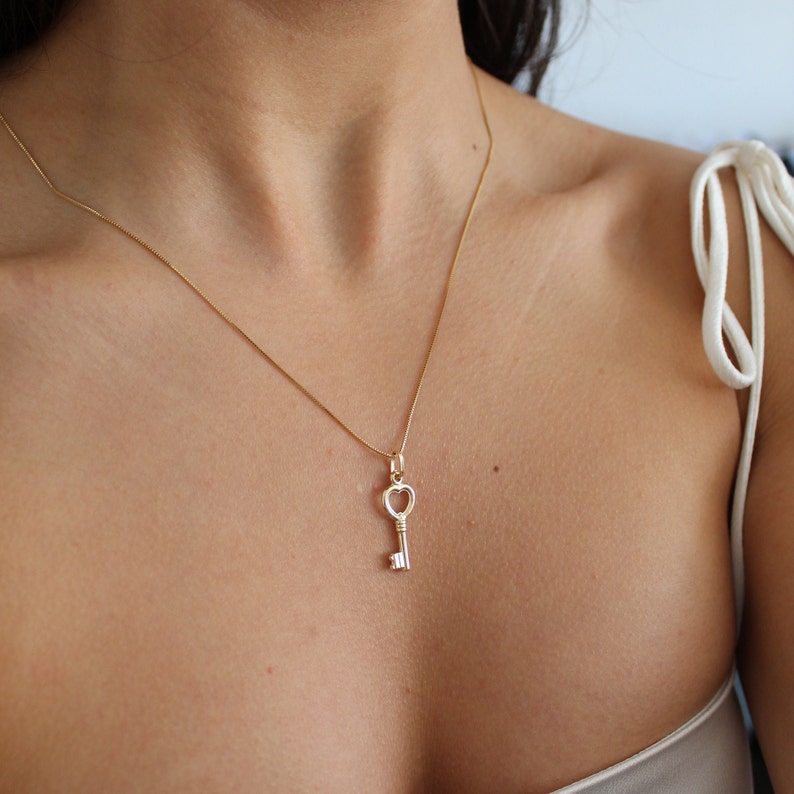 Peut inclure: Un collier en cha&icirc;ne dor&eacute;e avec un pendentif en forme de cl&eacute; de c&oelig;ur.