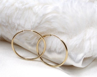 Pode incluir: Um par de brincos de argola de ouro. Os brincos são simples e elegantes, e seriam uma ótima adição a qualquer coleção de joias.