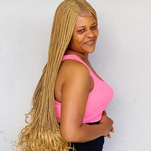 Peluca trenzada ElegantWigs. Trenza central francesa con rizos dorados. Cierre de 76 cm.