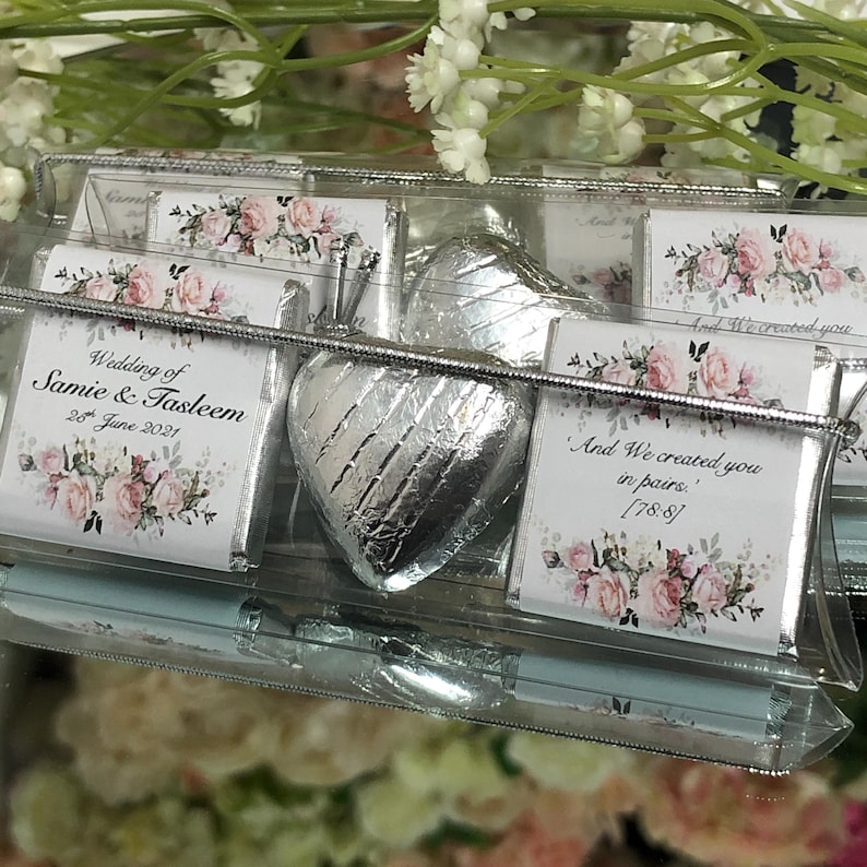 May include: A clear plastic bag filled with small, individually wrapped chocolate favors. The chocolates are decorated with floral designs and the text "Wedding of Samie & Tasleem 28 June 2021" and "And We created you in pairs, [78:8]"