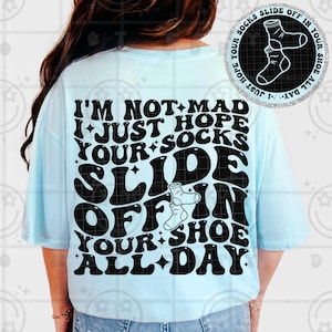 May include: A light blue t-shirt with the text "I'M NOT MAD I JUST HOPE YOUR SOCKS SLIDE OFF IN YOUR SHOE ALL DAY" in black. The shirt also features a graphic of socks and shoes.