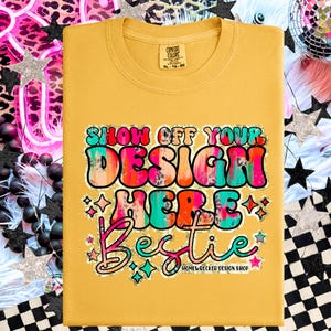 May include: A mustard yellow t-shirt with a colorful graphic that says "Show Off Your Design Here Bestie" with glitter accents. The graphic is in a retro style with a leopard print pattern. The text "Homewrecker Design Shop" is at the bottom of the graphic.