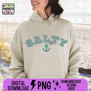 May include: A light beige hoodie with a turquoise blue and silver glitter design that says "Salty" with an anchor underneath.