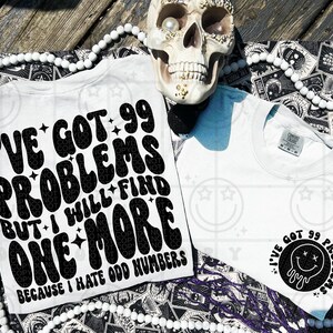 Puede incluir: Dos camisetas blancas con texto negro. Una dice "I'VE GOT 99 PROBLEMS BUT I WILL FIND ONE MORE BECAUSE I HATE ODD NUMBERS." La otra tiene un círculo negro con una carita sonriente derritiéndose y el texto "I'VE GOT 99 PROBLEMS."