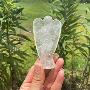 Peut inclure: Une figurine d'ange en cristal de quartz clair sculpt&eacute;e en forme d'ange avec les ailes d&eacute;ploy&eacute;es. La figurine est en cristal de quartz clair et a un aspect naturel et nuageux.