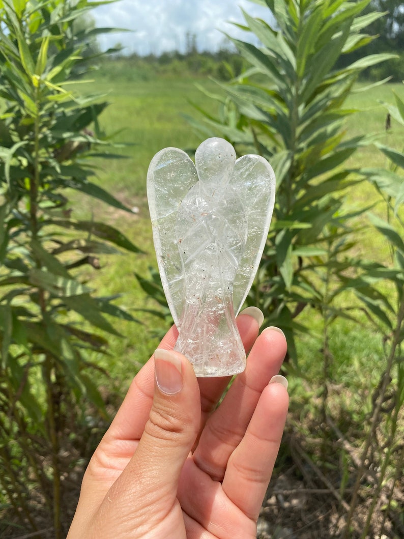 Peut inclure: Une figurine d'ange en cristal de quartz clair sculpt&eacute;e en forme d'ange avec les ailes d&eacute;ploy&eacute;es. La figurine est en cristal de quartz clair et a un aspect naturel et nuageux.