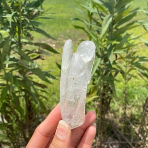 Peut inclure: Un cristal de quartz clair sculpt&eacute; en forme d'ange. L'ange a des ailes et une longue robe flottante. Le cristal est translucide et a un l&eacute;ger &eacute;clat.