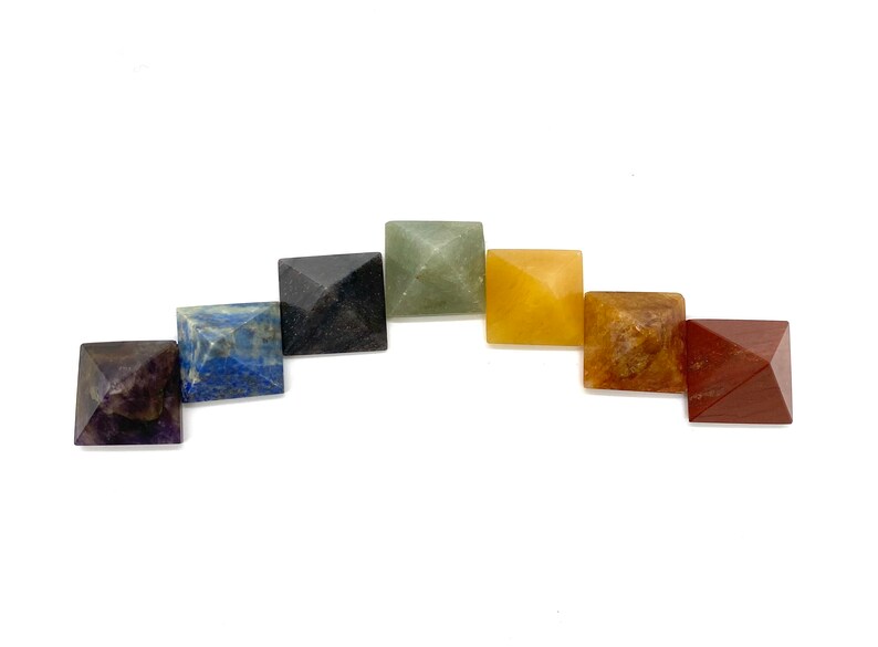 May include: Seven chakra pyramid crystals in a rainbow color arrangement. The crystals are amethyst, lapis lazuli, sodalite, black obsidian, green aventurine, citrine, and red jasper.