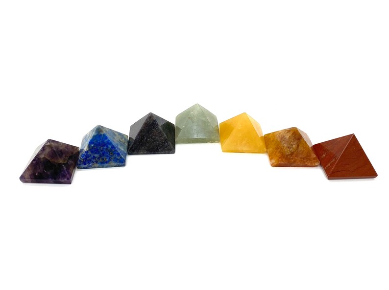 May include: Set of seven chakra crystal pyramids in various colors, including amethyst, lapis lazuli, black obsidian, green aventurine, citrine, carnelian, and red jasper.