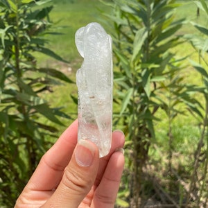 Peut inclure: Un cristal de quartz clair sculpt&eacute; en forme de deux figures qui s'embrassent. Le cristal est lisse et poli, avec des inclusions internes visibles.