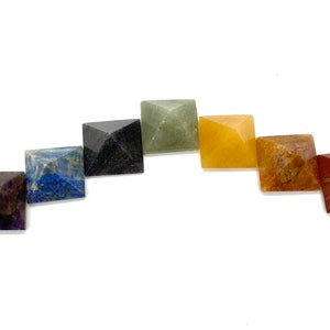 May include: Seven chakra crystal pyramids in a rainbow color arrangement. The pyramids are made of amethyst, lapis lazuli, sodalite, green aventurine, citrine, carnelian, and red jasper.
