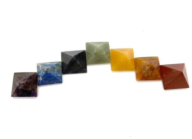 May include: Seven chakra crystal pyramids in a rainbow color arrangement. The pyramids are made of amethyst, lapis lazuli, sodalite, green aventurine, citrine, carnelian, and red jasper.