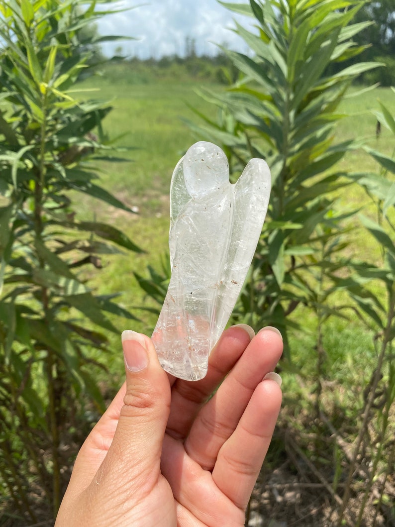 Peut inclure: Une figurine d'ange en cristal de quartz clair sculpt&eacute; dans un cristal naturel. L'ange est debout, les ailes d&eacute;ploy&eacute;es.