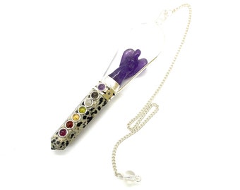 May include: A clear quartz pendulum with a silver chain and a small amethyst angel inside. The pendulum is adorned with seven chakra stones in a row.