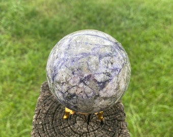 May include: A purple and grey crystal sphere on a gold stand. The sphere has a swirling pattern of purple and grey.
