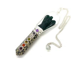 May include: A green angel shaped pendulum with a silver chain and a clear crystal at the end. The pendulum is made of a speckled stone with seven colored stones representing the chakras.