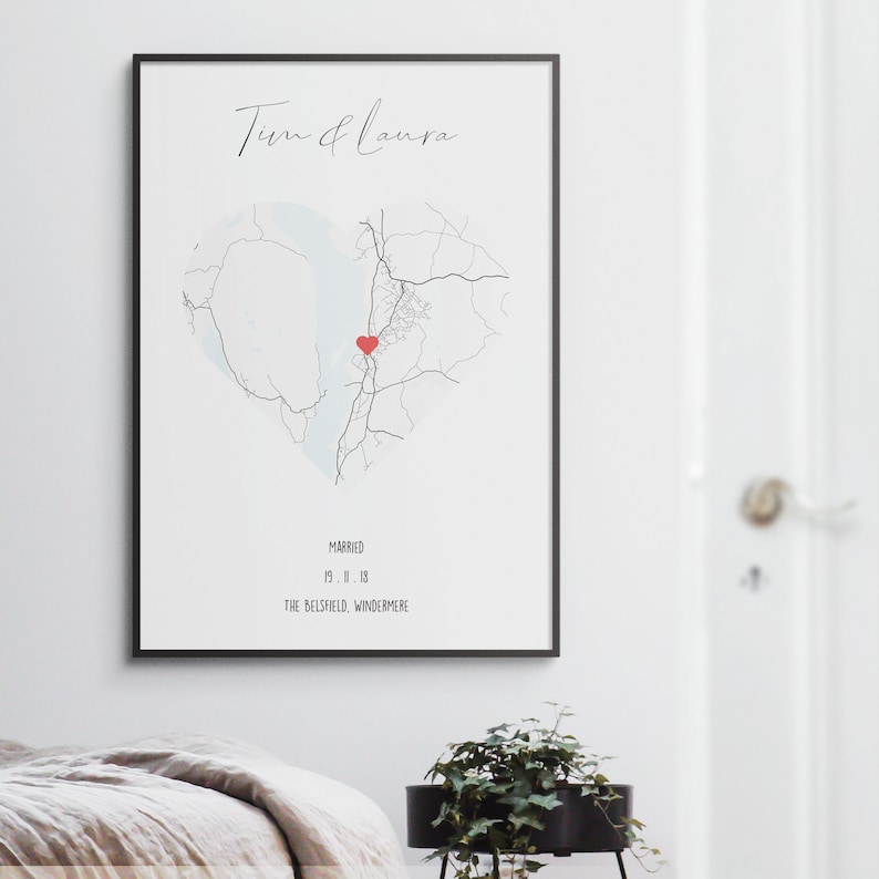 May include: A black and white map of a heart shape with a red heart in the center. The text "Tim & Laura" is at the top of the map. The text "Married 19.11.18 The Belfield, Windermere" is at the bottom of the map.