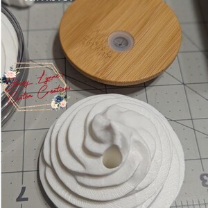 May include: A 20oz glass tumbler with a bamboo lid and a white, textured, decorative top. The bamboo lid is round with a clear plastic stopper. The white top has a spiral design. The text "20oz Glass tumbler" is visible.