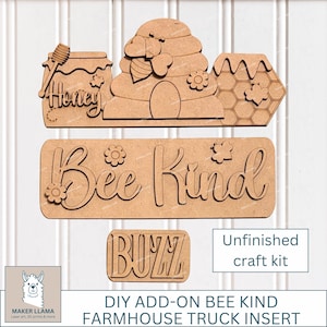 May include: Unfinished wooden craft kit with bee-themed cutouts. Includes a jar labeled "Honey", a beehive, a honeycomb, the phrase "Bee Kind", and the word "Buzz". Perfect for DIY farmhouse truck inserts.