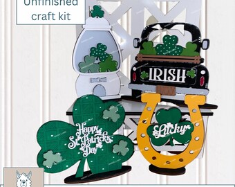 May include: Unfinished wooden craft kit for St. Patrick's Day. The kit includes a shamrock, a truck with the word "IRISH" on the back, a horseshoe with the word "Lucky" on it, and a gumball machine with shamrocks inside.