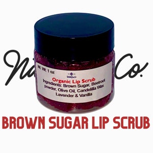 May include: A small glass jar with a black lid filled with a pink and red lip scrub. The label reads "Organic Lip Scrub" and lists the ingredients: Brown Sugar, Beetroot powder, Olive Oil, Candelilla Wax, Lavender & Vanilla. The jar is labeled with "NL Wt: 1 oz".