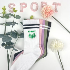May include: A set of five pairs of socks, with one pair featuring a green embroidered forest design and the word "FOREST". The socks are white, black, pink, purple, and green.