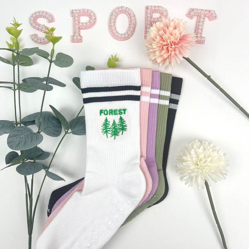 May include: A set of five pairs of socks, with one pair featuring a green embroidered forest design and the word "FOREST". The socks are white, black, pink, purple, and green.