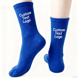 May include: A pair of royal blue socks with the text "Custom Text Logo" in white on the cuff. The socks are ribbed and appear to be made of a soft material. The socks are displayed on a white background.