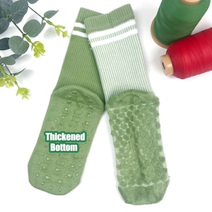 May include: A pair of green socks with white stripes. The socks have a textured bottom with the words "Thickened Bottom" printed on one sock.