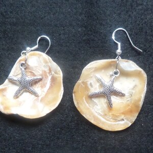 May include: A pair of earrings made from seashells with silver starfish charms.