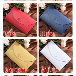May include: A collection of eight colorful envelopes in pink, orange, red, blue, golden, white, yellow, and black. Each envelope has a heart-shaped closure. The word for each color is displayed below each envelope.
