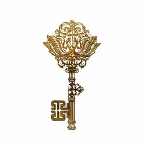 May include: A gold-colored ornate key with a decorative design featuring two birds with wings outstretched. The key has a long, slender shaft and a detailed, intricate head.