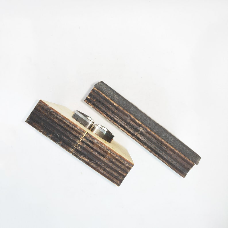 May include: Two pieces of wood with a dark brown stain. One piece has two metal rings attached to it.