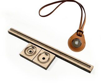 Könnte beinhalten: Ein Satz Lederhandwerkzeuge zur Herstellung eines Leder-Schlüsselanhängers. Das Set enthält eine Metallstanzform, eine Holzbasis und ein Lederband mit einem Apple-Logo.