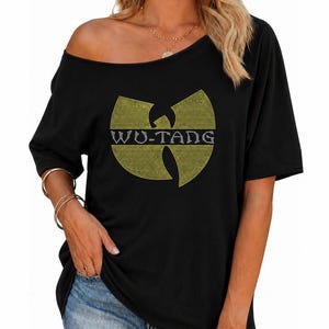 May include: A black short-sleeved t-shirt with an off-the-shoulder neckline. The front features a large Wu-Tang Clan logo graphic created with yellow and white rhinestones, with the text WU-TANG clearly visible across the center of the design.