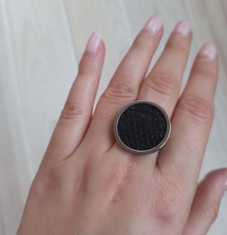 May include: A black ring with a textured surface and a silver metal band.