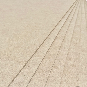 K&ouml;nnte beinhalten: Ein Stapel aus sechs beigefarbenen, unbehandelten Holzplatten. Die Platten sind glatt und haben eine leicht strukturierte Oberfl&auml;che.