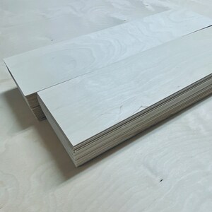 May include: A stack of white wood planks, likely for crafting or woodworking projects.