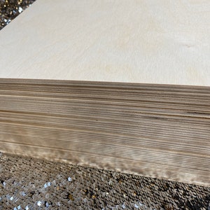 K&ouml;nnte beinhalten: Ein Stapel unfertiger, hellbrauner Holzplatten. Die Platten sind glatt und haben eine nat&uuml;rliche Holzmaserung.