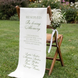 May include: A wooden folding chair draped with a white fabric sign featuring the text RESERVED In loving Memory FOR THOSE WHO CANNOT BE HERE TODAY BUT ARE FOREVER PRESENT IN OUR HEARTS, TODAY AND ALWAYS, followed by five names, with a bouquet of baby's breath.